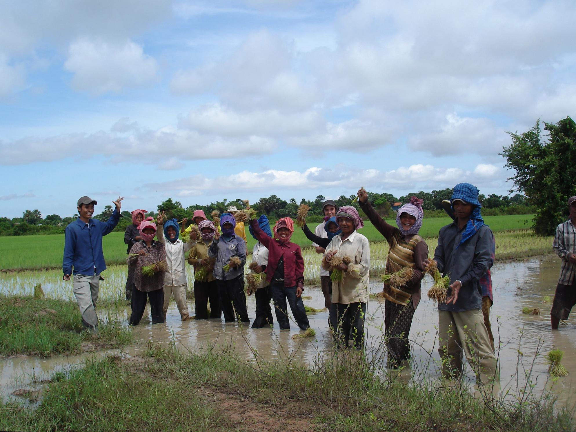 A group of local men and women are standing in a river during a Khmer Project ran by Projects Abroad Community Volunteers. Local people are posing for a picture in a river during a Cultural immersion project in Cambodia.
